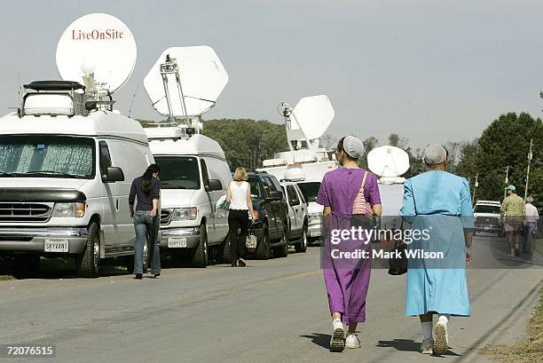 Two Amish women walk past a line of satellite trucks that are parked October 3, 2006 in Nickel Mines, Pennsylvania. According to officials a milk...