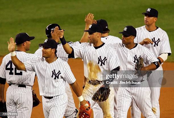 Shortstop Derek Jeter of the New York Yankees high fives his teammates after making the final double play to win Game One of the American League...