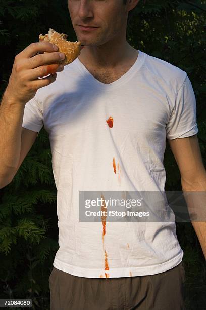 man spilling ketchup whilst eating hamburger - adults eating hamburgers foto e immagini stock
