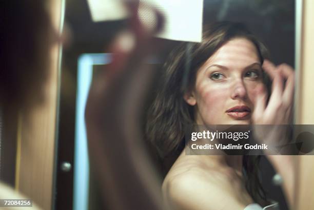 young woman looking at herself in mirror - vanidad fotografías e imágenes de stock