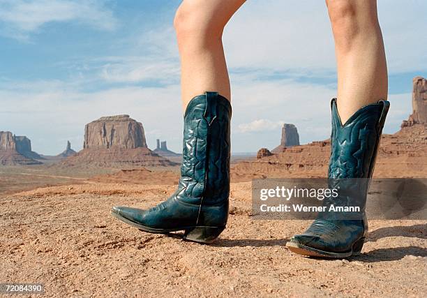 woman standing in desert wearing cowboy boots - cowboy stock-fotos und bilder