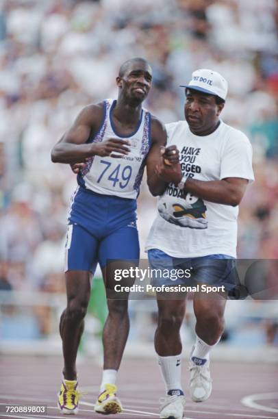 English track athlete Derek Redmond of the Great Britain team is aided by his father Jim Redmond to complete a full lap of the track after tearing...