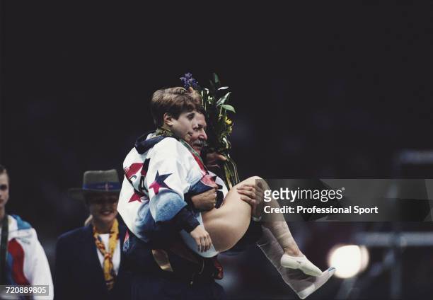 American gymnast Kerri Strug is carried back by coach Bela Karolyi after receiving her gold medal on the medal podium following a foot injury, after...