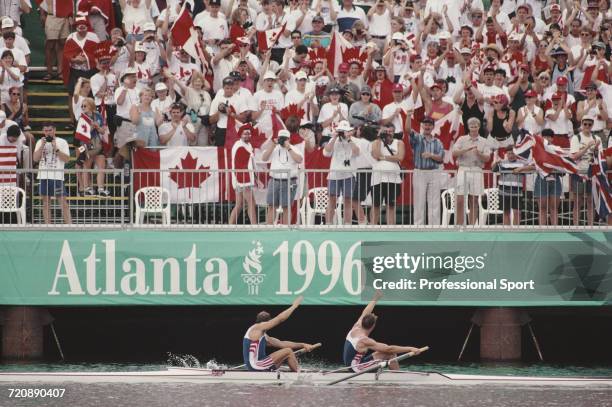 English rowers Matthew Pinsent and Steve Redgrave wave to spectators from their boat after finishing in first place for the Great Britain team to win...