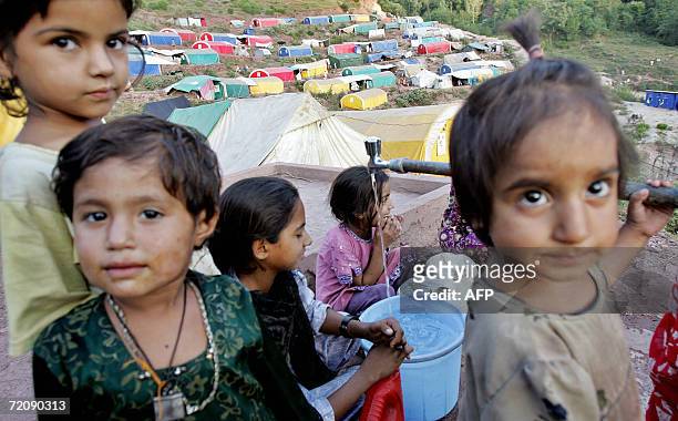 Muzaffarabad, PAKISTAN: Young Pakistani Kashmiri earthquake survivors fill a bucket with drinking water near a makeshift camp in a mountain area of...