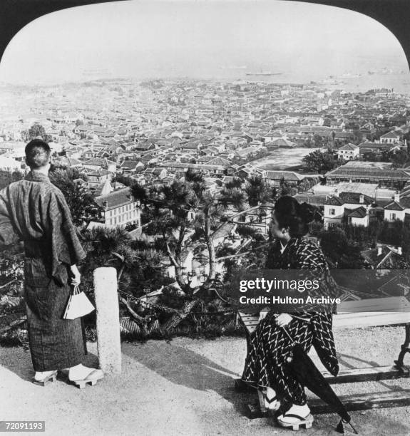 Couple in traditional dress admiring the view over the Japanese port city of Kobe from Suwayama, 1905.