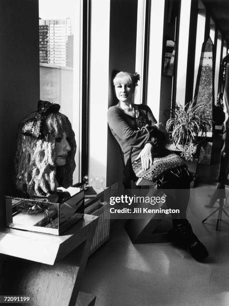 English fashion designer Zandra Rhodes, circa 1990. To the left stands a glass mosaic bust of her, by sculptor and colleague Andrew Logan.