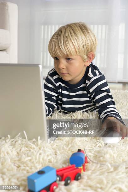 boy (4-5 years) lying on floor and using a laptop - alfombra raton fotografías e imágenes de stock
