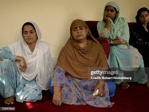 The wife of Mohammad Rameez Mian and family members look on sadly while speaking about her dead husband on August 3, 2005 in Pattan, Kashmir. Mian...