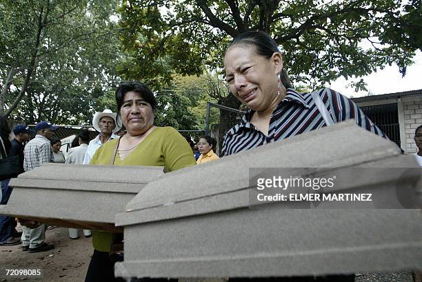 Tegucigalpa, HONDURAS: Dos muejeres cargan, en la morgue del Ministerio Publico en Tegucigalpa, ataudes de dos de los seis ninos muertos, junto a...
