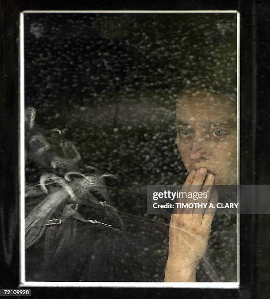 Nickel Mines, UNITED STATES: An Amish woman peers out the window of a buggy in the funeral procession of Anna Mae Stoltzfus, age 12, a victim of the...