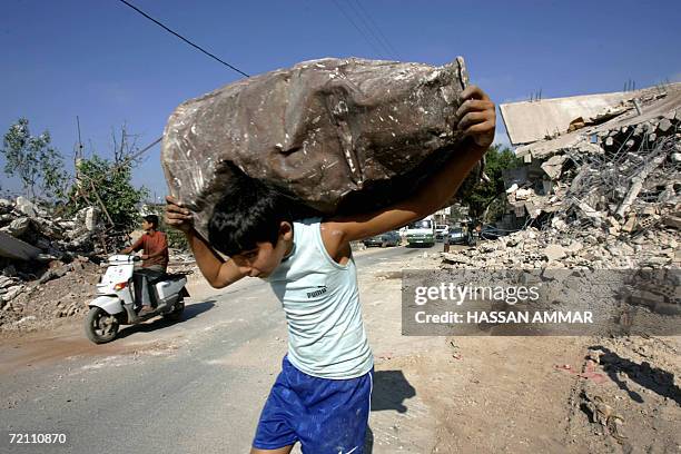 Lebanese youth carries a damaged barrel after it was recovered from the rubble of buildings destroyed by Israeli airstrikes during the 34-day...