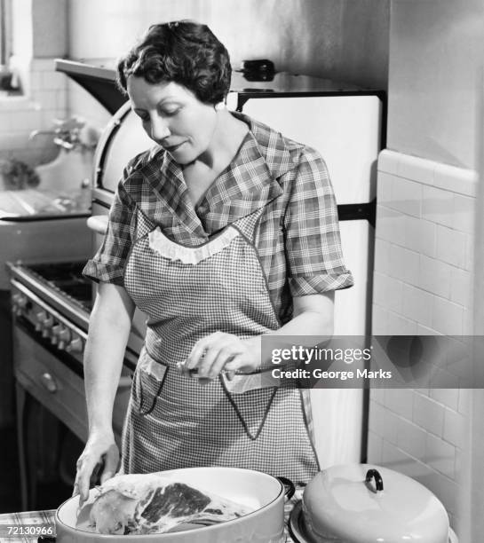 woman seasoning meat in roasting dish (b&w) - 1950 females only housewife stockfoto's en -beelden