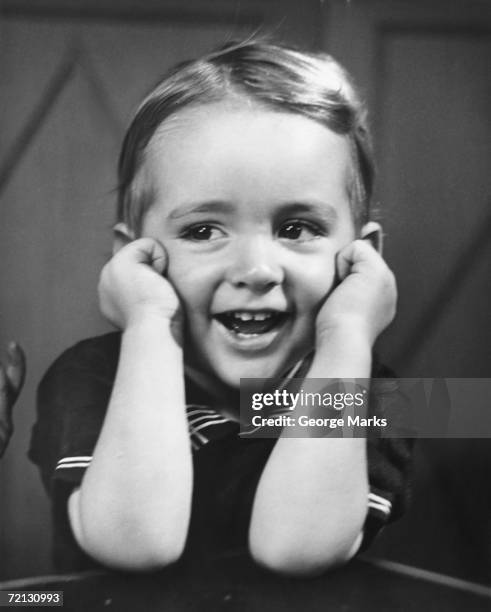 boy (4-5) sitting at table, smiling (b&w) - kinder 40er jahre stock-fotos und bilder