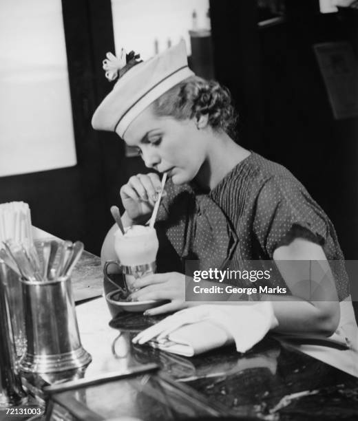 young woman in fancy hat drinking ice cream soda (b&w) - soda fountain stock pictures, royalty-free photos & images