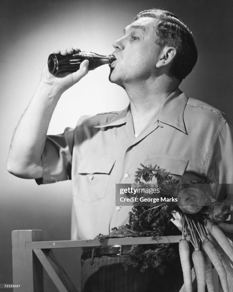 Man drinking cola from bottle in studio (B&W)