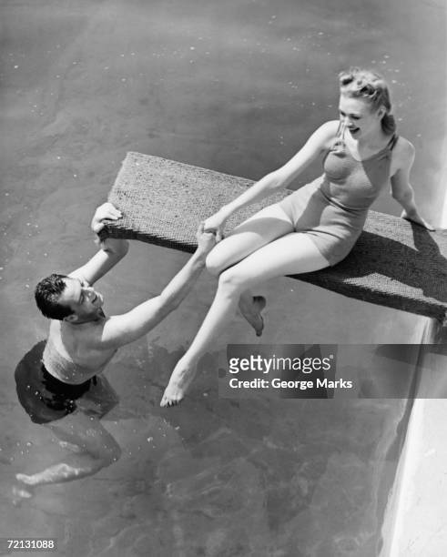 frau sitzt auf wassersprung-brett, man unweigerlich ihre hand - women swimming pool retro stock-fotos und bilder