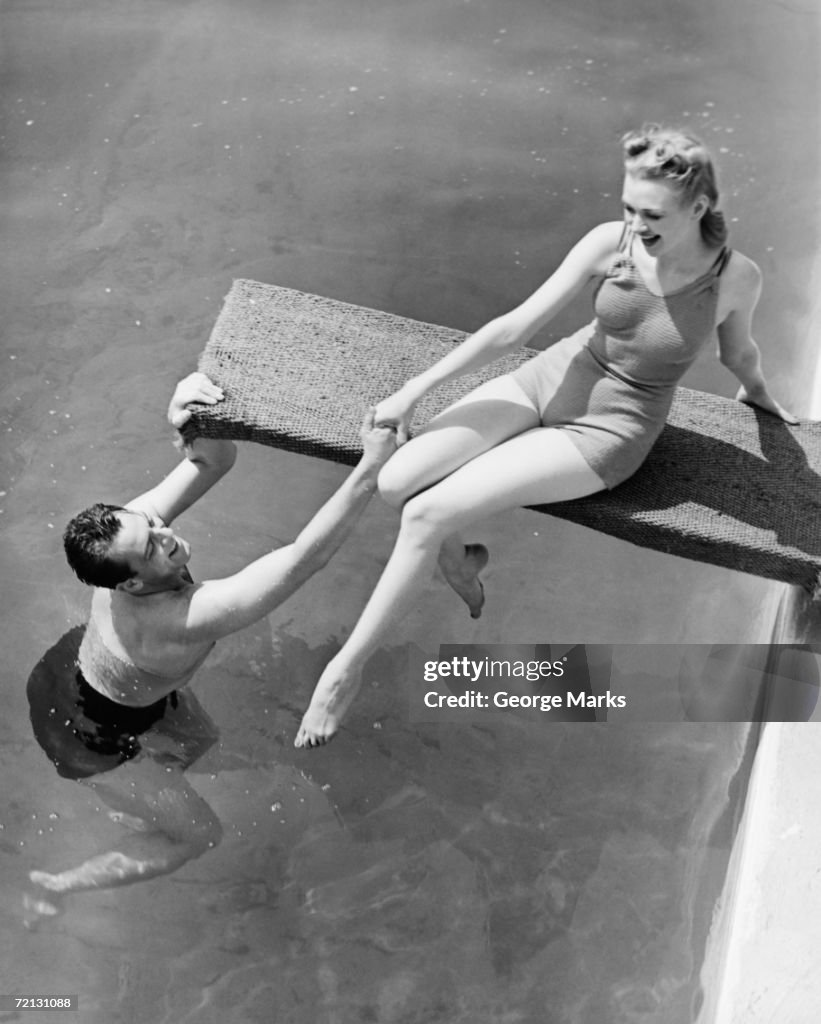 Mulher sentada na Prancha de mergulho, homem segurando a mão