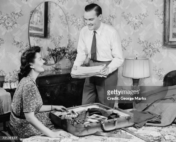 woman assisting man packing suitcase (b&w) - 1940s bedroom stock pictures, royalty-free photos & images