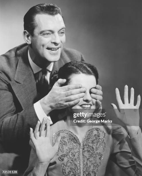 man standing behind woman, covering her eyes (b&w) - 1950s couple stock pictures, royalty-free photos & images