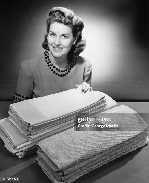 woman sitting at pile of ironed linen and towels (b&w), portrait - housewife stock pictures, royalty-free photos & images