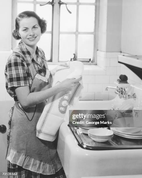 young woman drying dishes in kitchen (b&w), portrait - 1950 females only housewife stock pictures, royalty-free photos & images