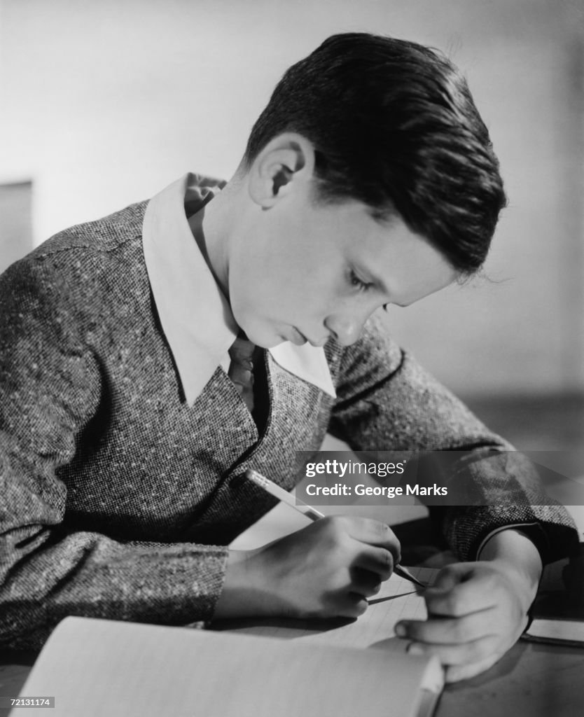 Boy (10-11) writing in notebook (B&W)