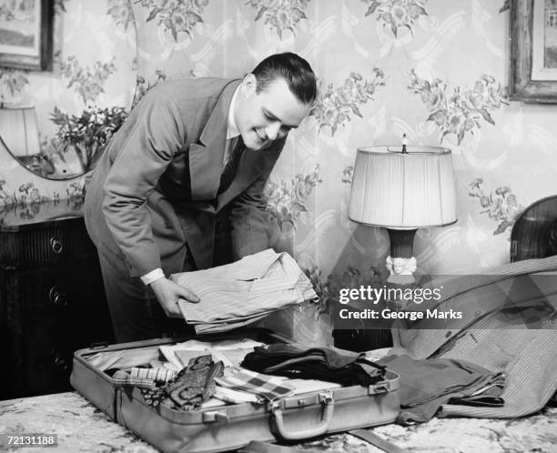 man packing suitcase in bedroom (b&w) - 1950s bedroom stock pictures, royalty-free photos & images