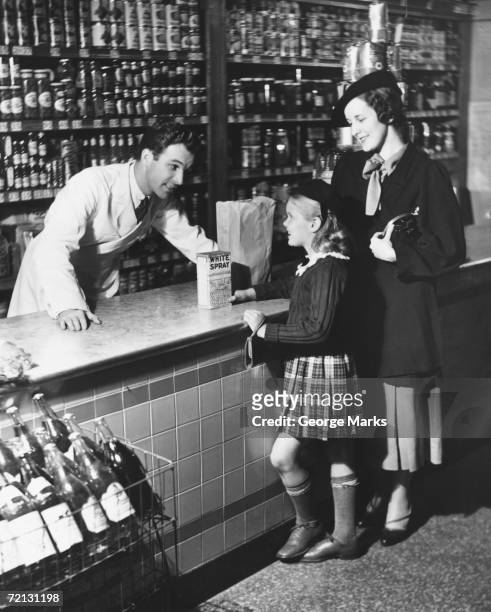 mother and daughter (8-9) standing at counter, talking to shop assistant (b&w) - assistant family stockfoto's en -beelden