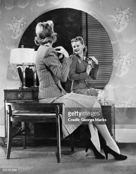 young woman pinning artificial flowers to jacket in front of mirror (b&w) - 1940s bedroom stock pictures, royalty-free photos & images