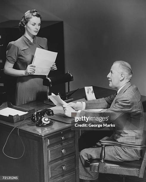 businessman sitting at desk talking to secretary (b&w) - 20th century stock pictures, royalty-free photos & images