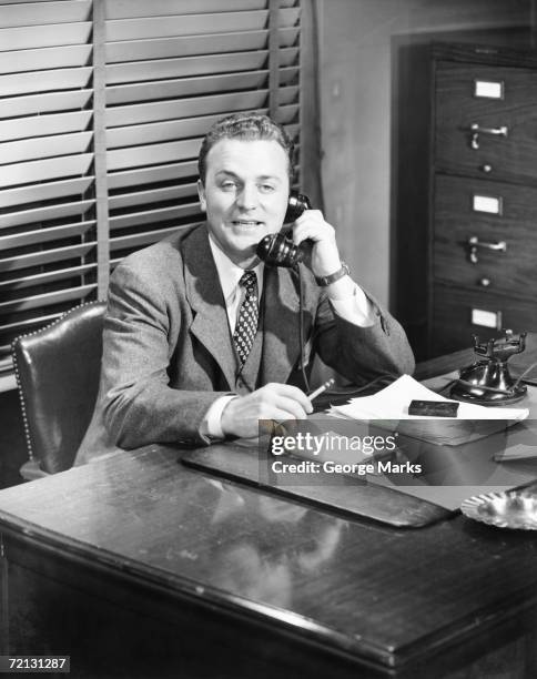 businessman talking on phone at desk (b&w) - 1950 phone stock pictures, royalty-free photos & images