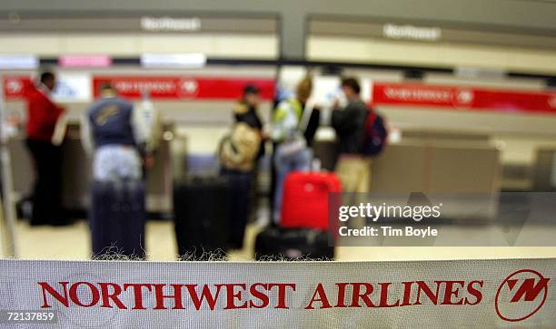 Travelers wait in line at the Northwest Airlines ticket counter beyond stanchion strapping at O'Hare International Airport October 10, 2006 in...