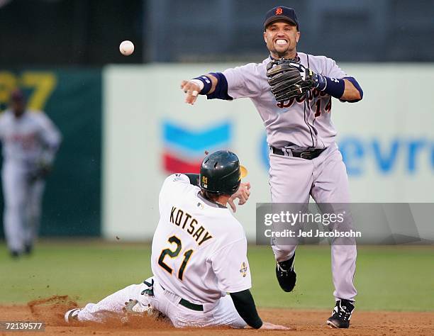 Infielder Placido Polanco of the Detroit Tigers completes a double play over Mark Kotsay of the Oakland Athletics to end the third inning of Game One...