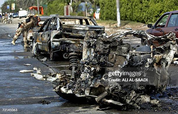 An Iraqi soldier inspects the wreckage of a car in southeast Baghdad, 11 October 2006 at the site where a car bomb and a roadside bomb exploded...