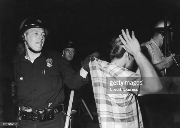 Policemen hunt for the killers of their colleague Richard Lefebre, following a period of rioting in the Watts area of Los Angeles, August 1965.