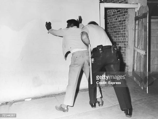 Policeman searches a suspect during rioting in the Watts area of Los Angeles, August 1965.