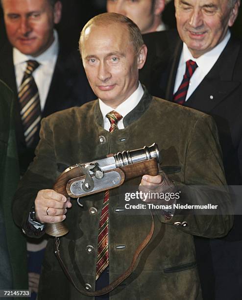 Russian President Vladimir Putin holds a "boeller" gun in his hand on October 11, 2006 in Aying near Munich, Germany. Putin is wearing a typical...