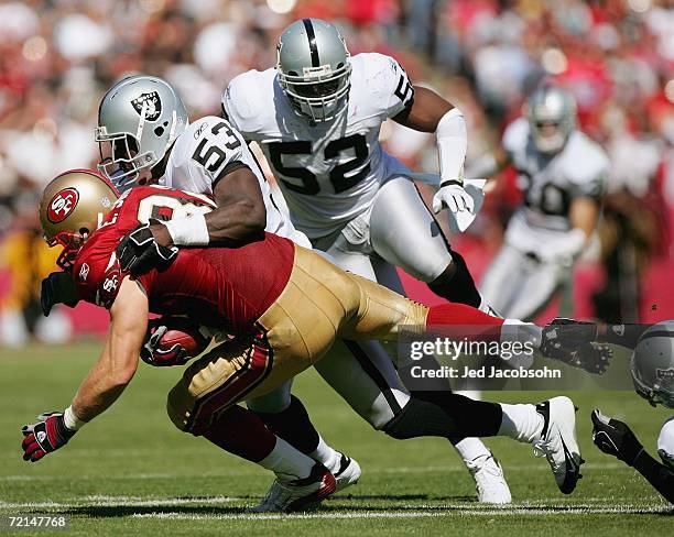 Linebacker Thomas Howard of the Oakland Raiders tackles tight end Eric Johnson of the San Francisco 49ers at Monster Park on October 8, 2006 in San...