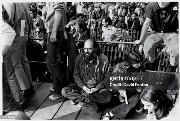 Clockwise from left, American Beat poet Allen Ginsberg sits with his hands clasped together in a meditative, cross-legged stance next to social...