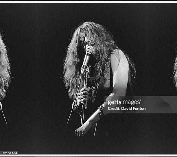American blues-influenced rock singer Janis Joplin sings with passion into a microphone as she performs with her eyes closed on a darkened stage at...