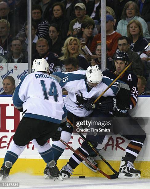 Ryan Smyth of the Edmonton Oilers fights for the puck with Ville Nieminen of the San Jose Sharks as Sharks teammate Jonathan Cheechoo skates in...