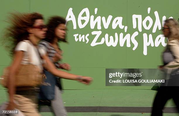 Greek people pass by 13 October 2006 a pre-electional kiosk of the conservative party candidate, Nikitas Kaklamanis, for Municipal and regional...
