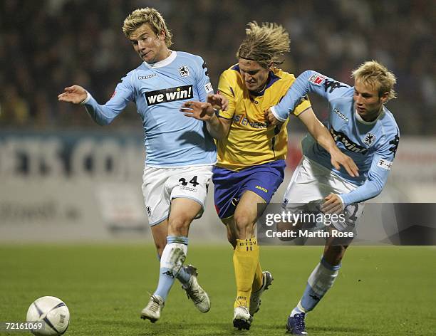 Tobias Schweinsteiger of Braunschweig is tackled by Daniel Baier and Christoph Burkhard of 1860 Munich during the Second Bundesliga match between...