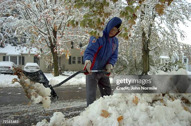 Donald Webber clears snow October 13, 2006 outside of Buffalo in Orchard Park, New York. A rare and record breaking early season snowfall closed a...