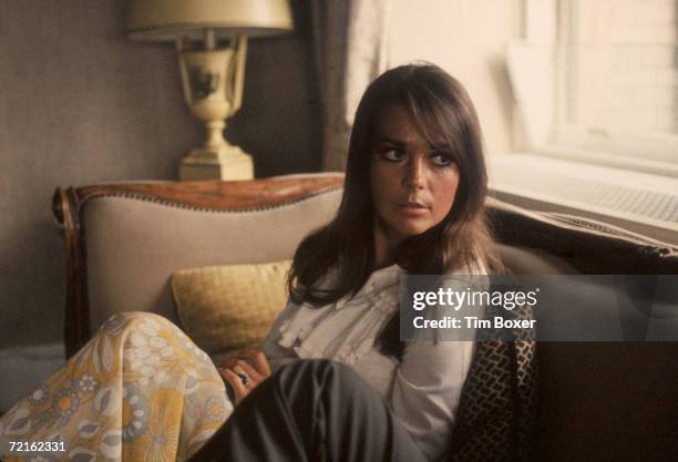 Portrait of American actress Natalie Wood as she sits on a sofa and looks over her shoulder, late 1960s.