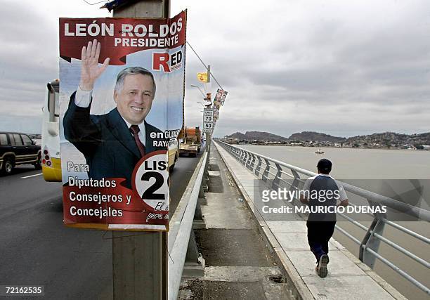Man runs past a poster of presidential candidate Leon Roldos, as he joggs through a bridge across the Guayas river 13 October in Guayaquil, Guayas...
