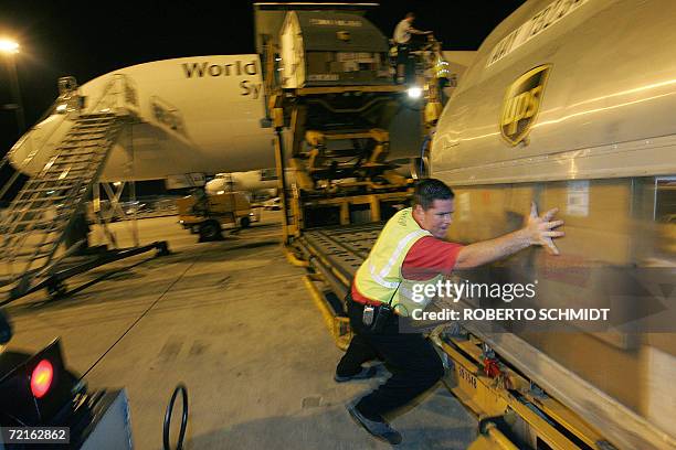 Cargo airport worker helps roll a United Parcel Service cargo container that was unloaded from a UPS airplane at Miami International airport in...