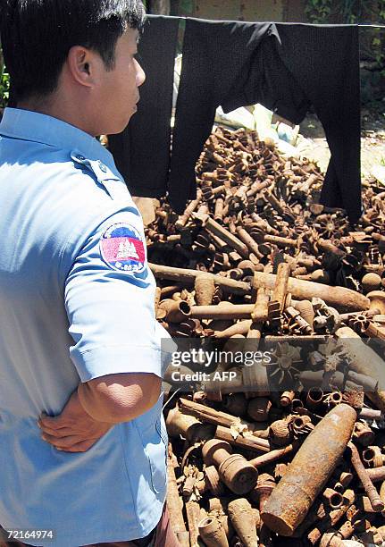 Deminer from the Cambodian Mine Action Center looks over a pile of derelict artillery shells and hand grenades at a scrap yard in Poipet, northwest...