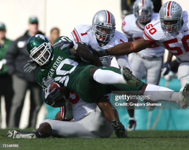 Jehuu Caulcrick of the Michigan State Spartans is tackled by Jay Richardson, Vernon Gholston and Marcus Freeman of the Ohio State Buckeys during...